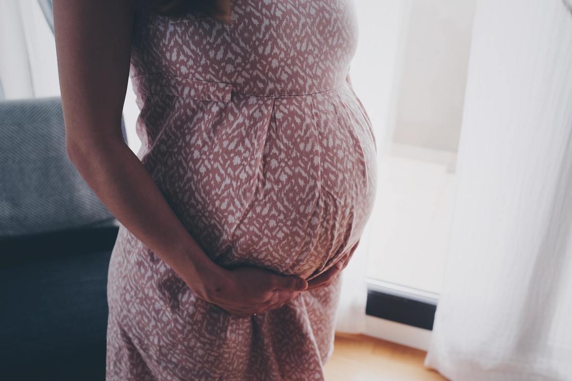 Pregnant woman receiving prenatal chiropractic treatment for low back pain in pink dress