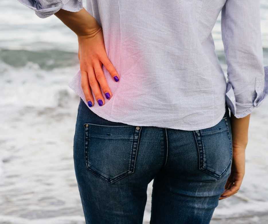 Lady in white shirt holding her low back