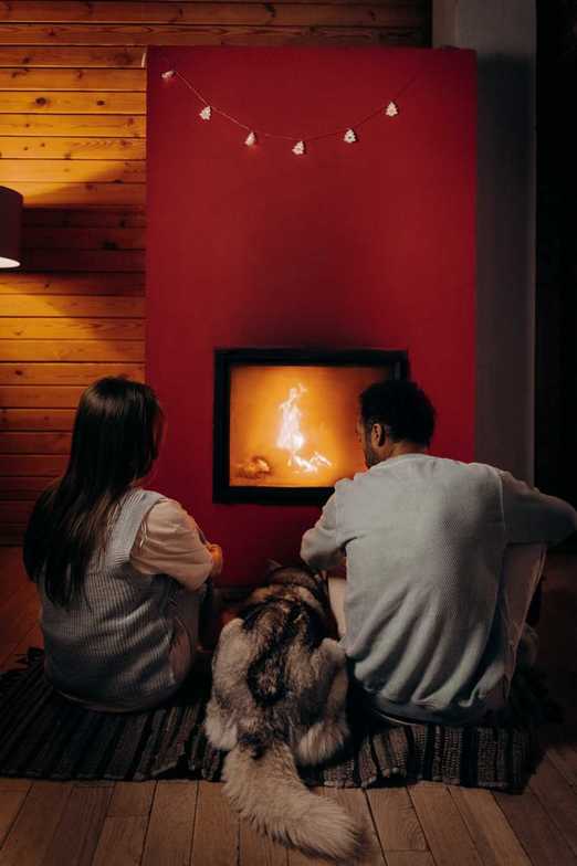 A naturopath and man sitting next to a fireplace with their dog