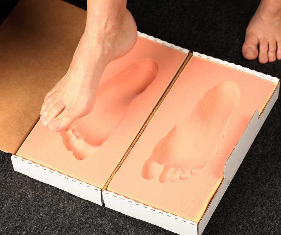 A foot placing an impression into an orthotic mold.